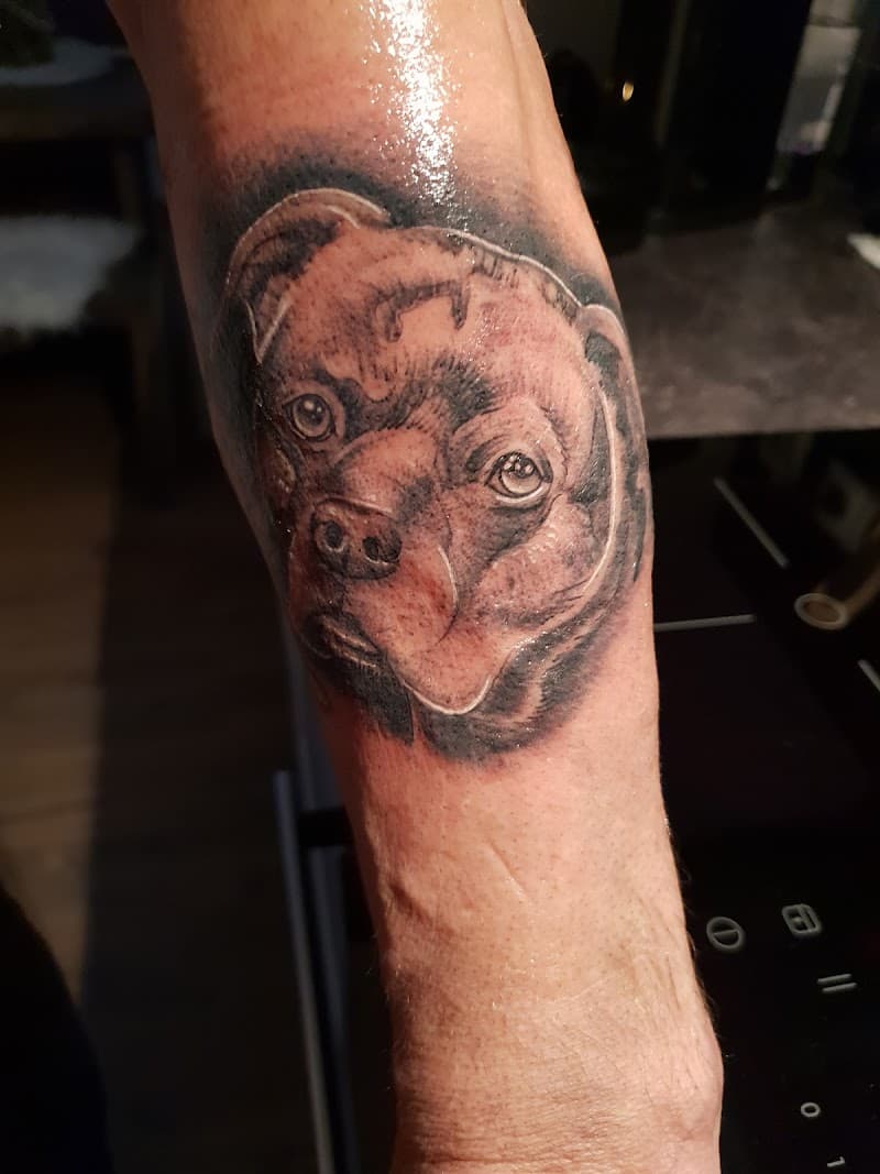 Realistisch portret van een hondenkop op de onderarm.