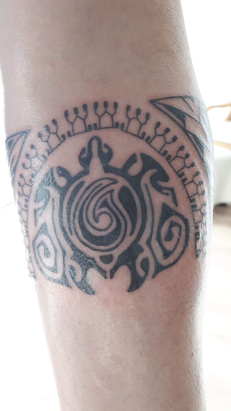 Blackwork schildpad tattoo met spiraal en patronen op onderbeen.