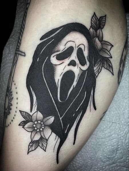 Blackwork Ghostface masker met bloemen op bovenbeen.