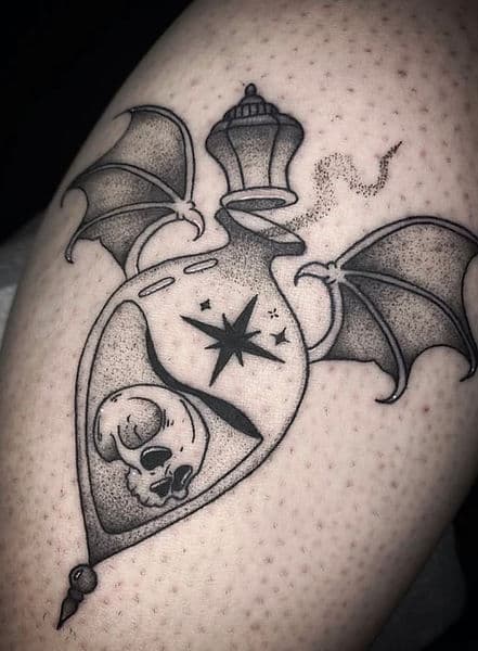 Blackwork tattoo van een gevleugelde toverdrankfles met een schedel en ster.