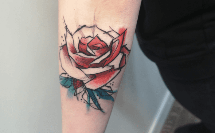 Schets en aquarel stijl roos tattoo op onderarm met rode en blauwe kleuren.
