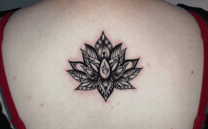 Zwart-wit lotusbloem tattoo met decoratieve patronen op de bovenrug.