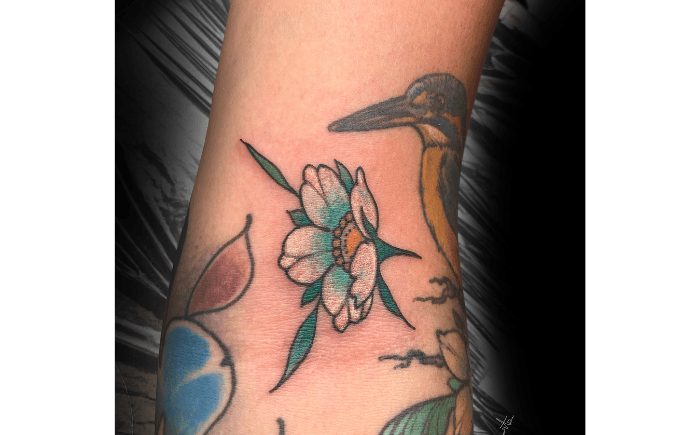 Neo-traditionele bloem tattoo met vogel op arm.
