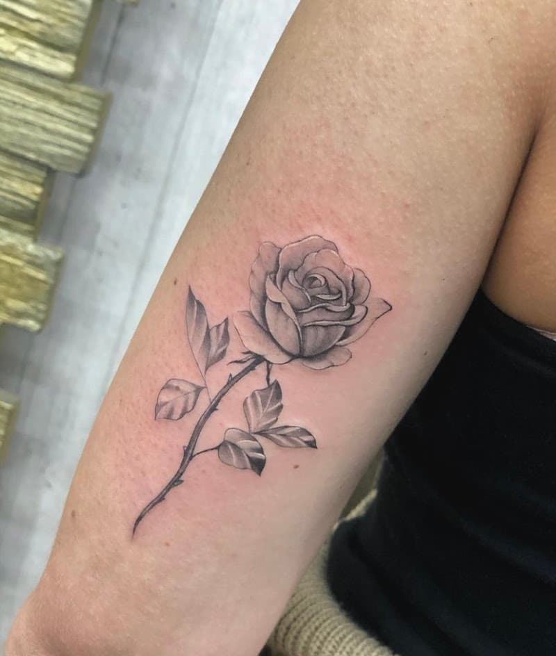 Realistische roos met steel en bladeren op bovenarm.