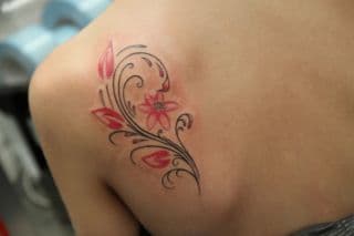 Sierlijke bloem met krullen op schouderblad.