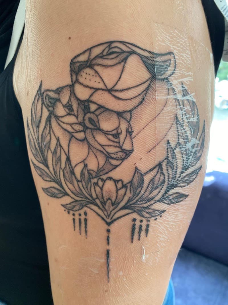 Geometrische leeuwin en welp met bladeren en ornamenten op bovenarm.