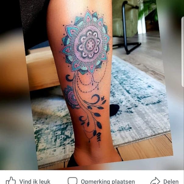 Kleurrijke mandala met bloemen en sierlijke lijnen op onderbeen.