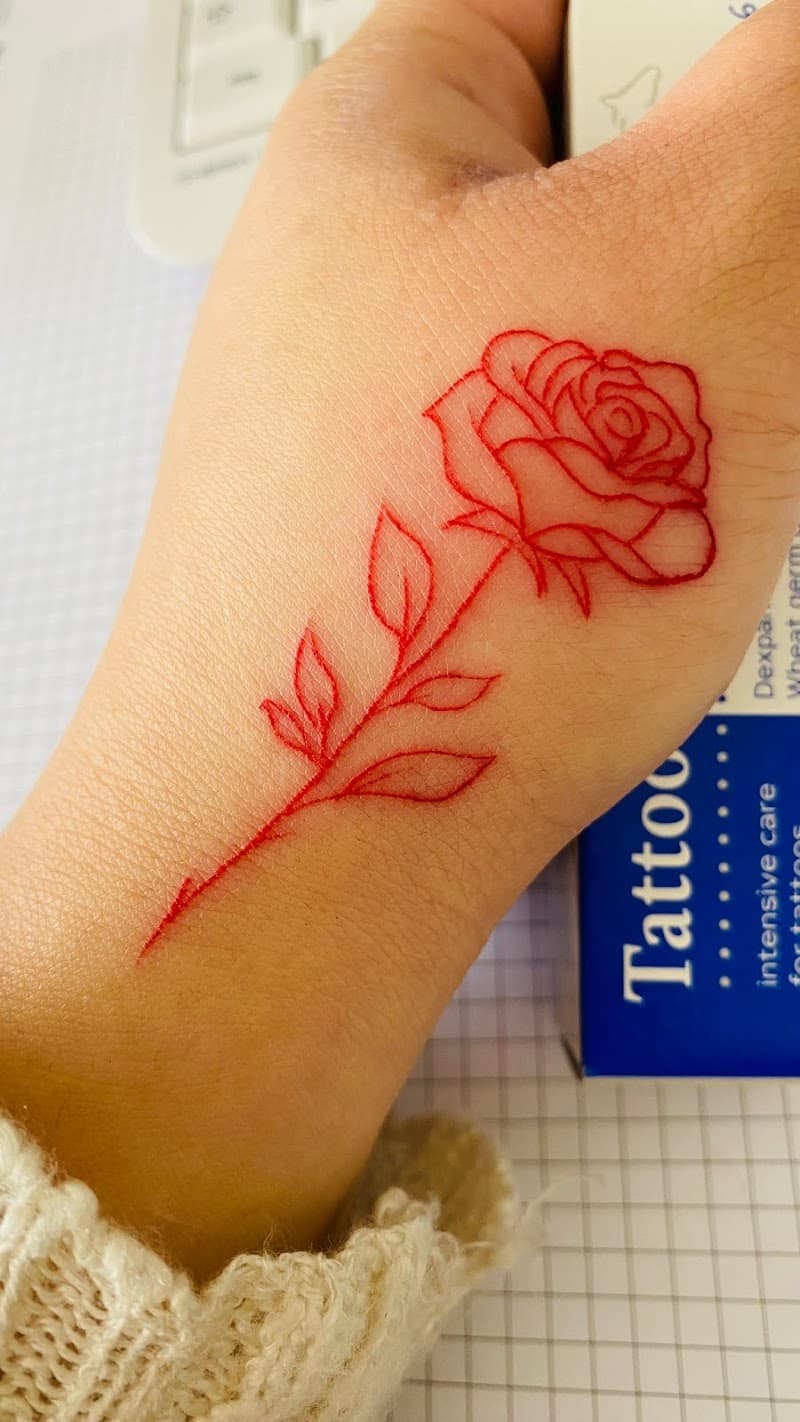 Rode fineline roos tattoo op de hand.