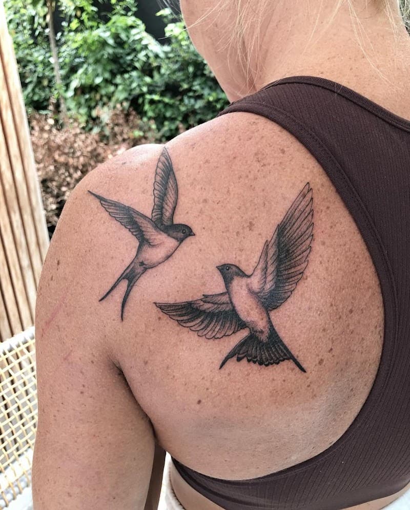 Twee gedetailleerde vliegende zwaluwen op het schouderblad.