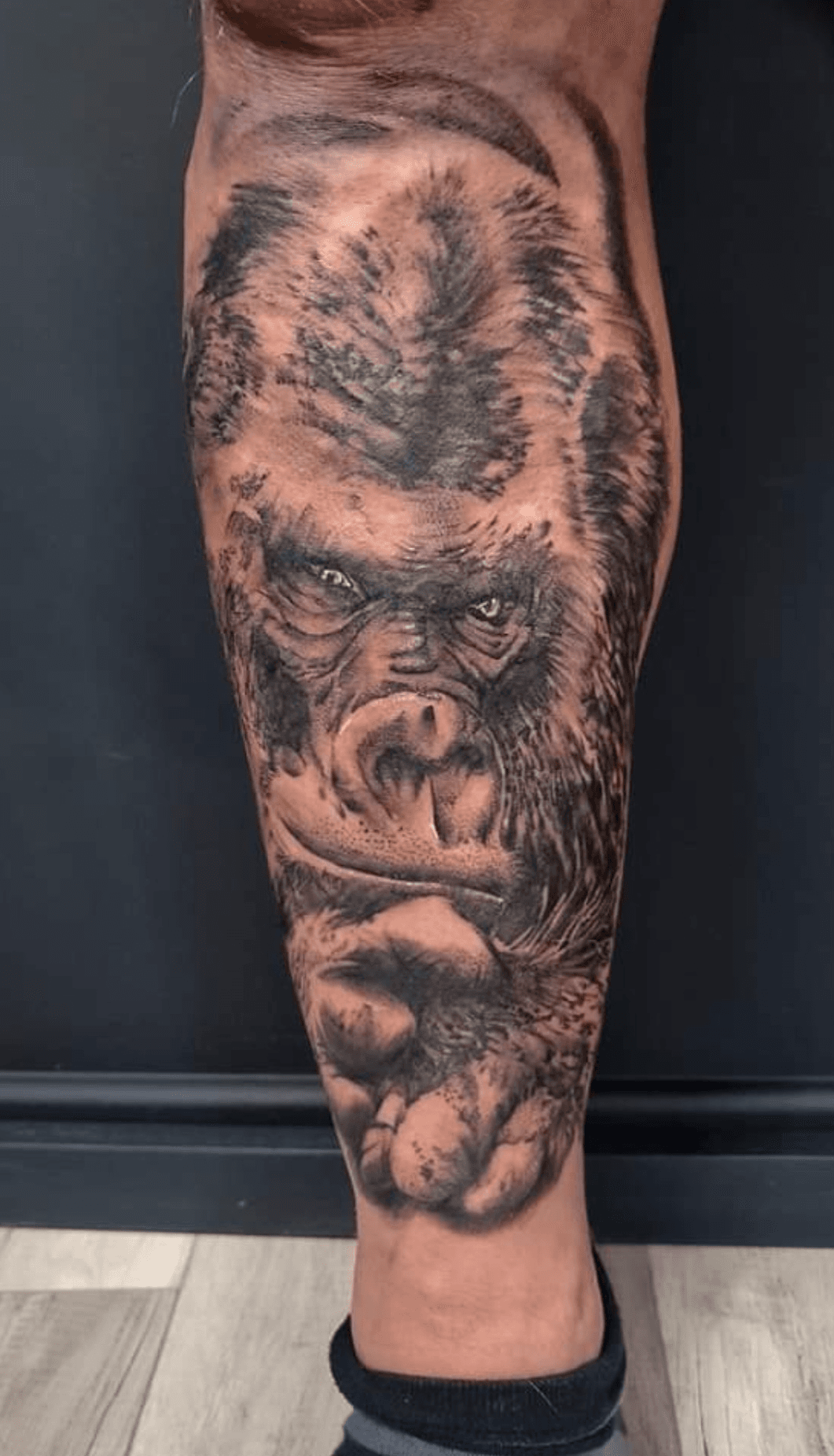 Realistische gorilla tattoo op onderbeen, zwart-wit.