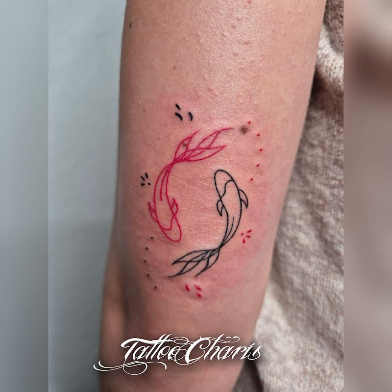 Fineline tattoo van twee koi vissen in yin yang vorm, rood en zwart.