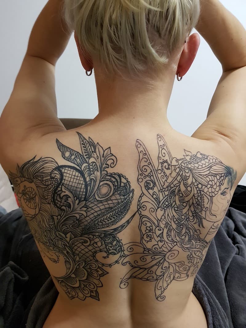 Grote rugtattoo met decoratieve patronen en een vrouwenprofiel.