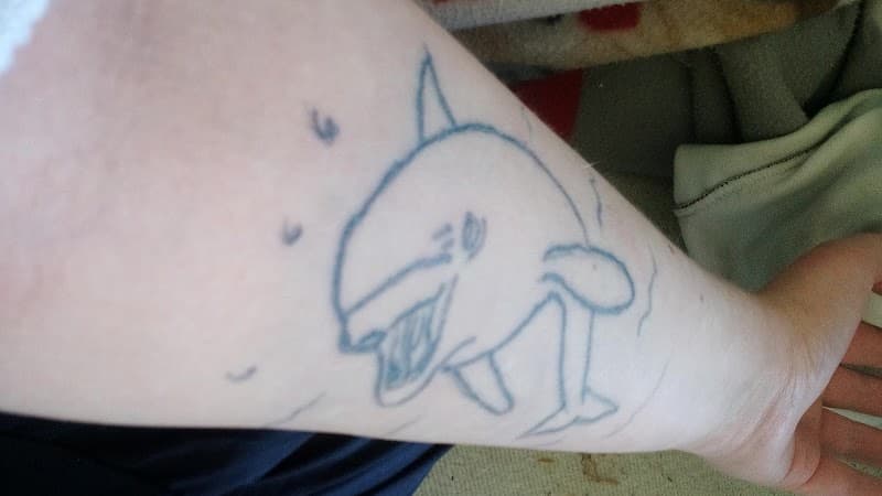 Eenvoudige lijntekening van een orka op de onderarm.