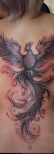 Grote zwart-wit feniks tattoo op de rug met sierlijke staart.