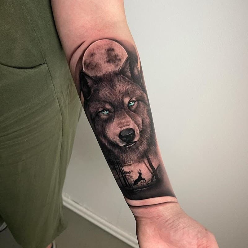 Realistische wolf met blauwe ogen, maan en hert op onderarm.