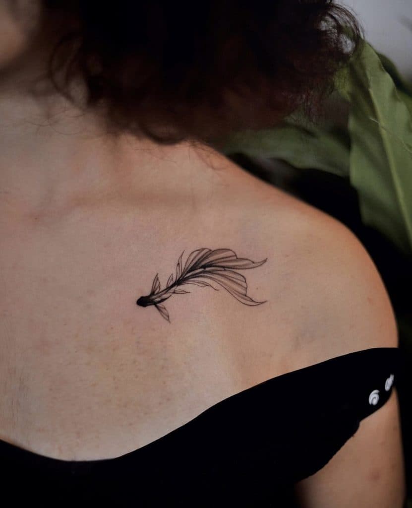 Fineline tattoo van een sierlijke vis op het sleutelbeen.