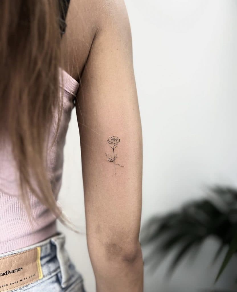 Minimalistische fineline roos op de achterkant van de bovenarm.