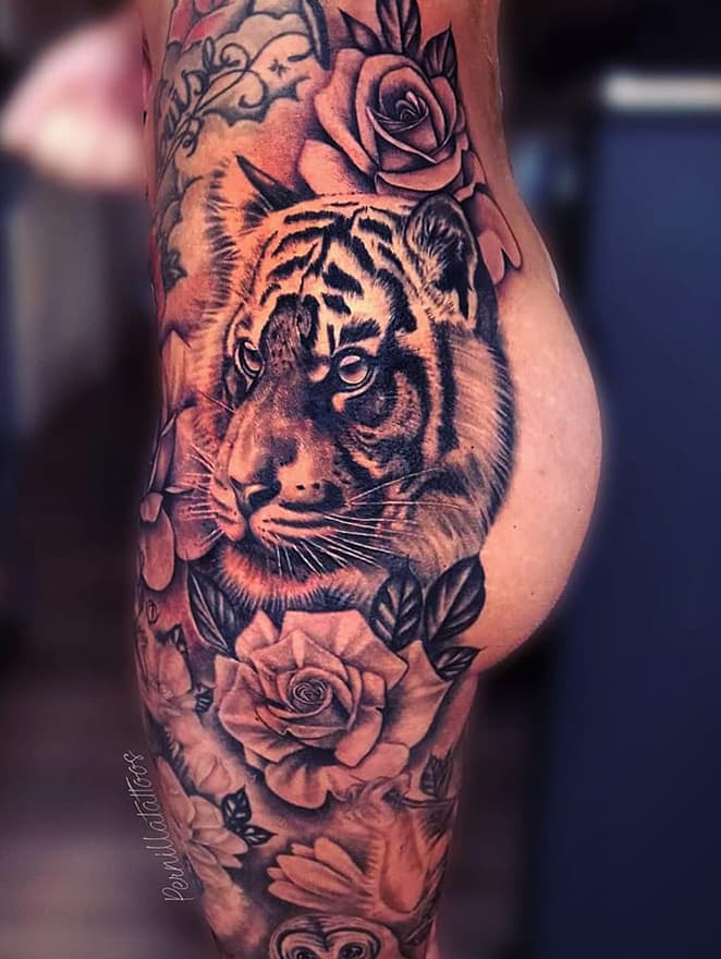 Realistische tijgerkop met rozen op bovenbeen en heup.