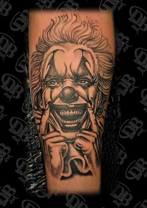 Zwart-wit tattoo van een lachende clown die zijn mondhoeken omhoog trekt.