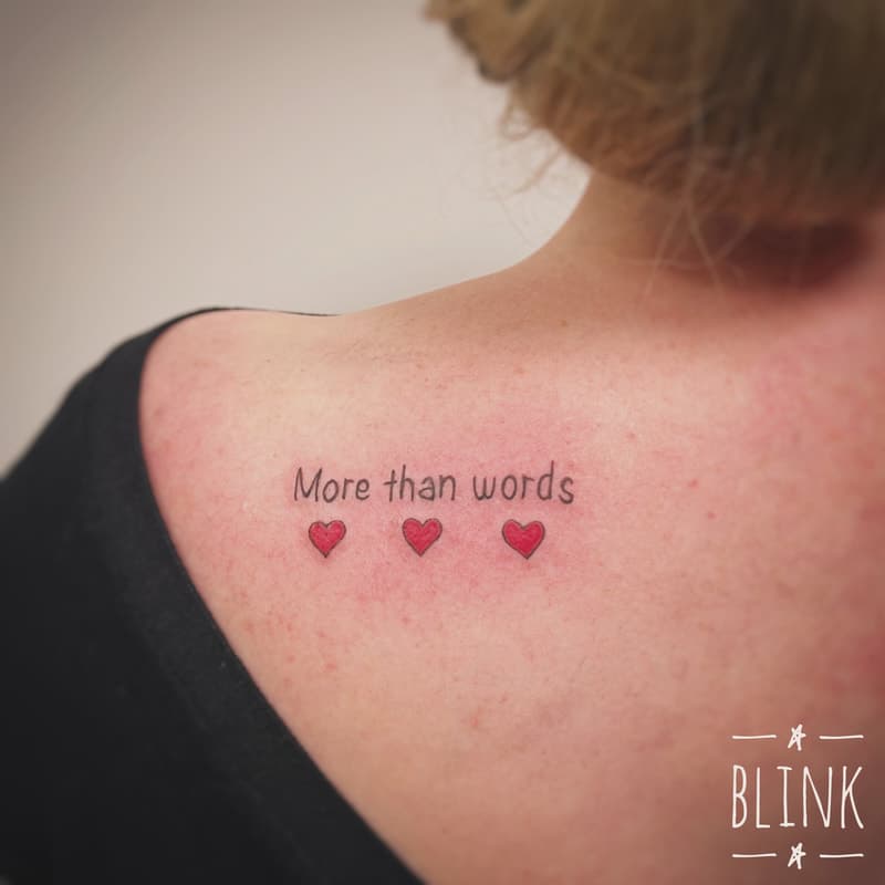 "More than words" tekst met drie rode hartjes op schouder.