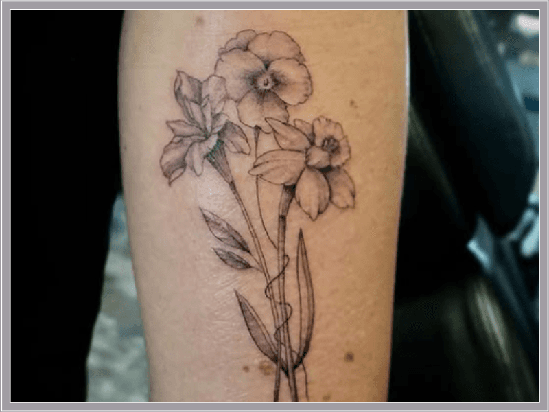 Fineline tattoo van een boeket met een viooltje, narcis en iris op de arm.