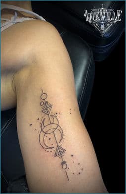 Geometrische maan en pijl tattoo met dotwork op bovenarm.