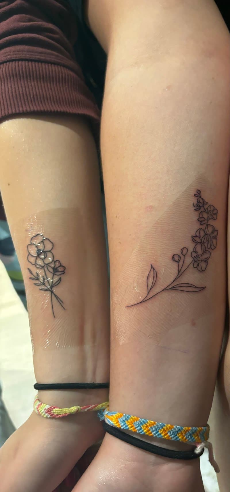 Twee fineline bloementattoos op onderarmen, één boeketje en één takje.