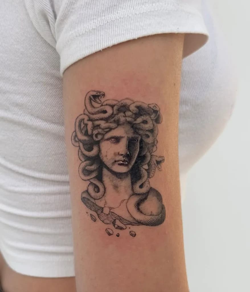 Gedetailleerde Medusa buste tattoo op bovenarm.