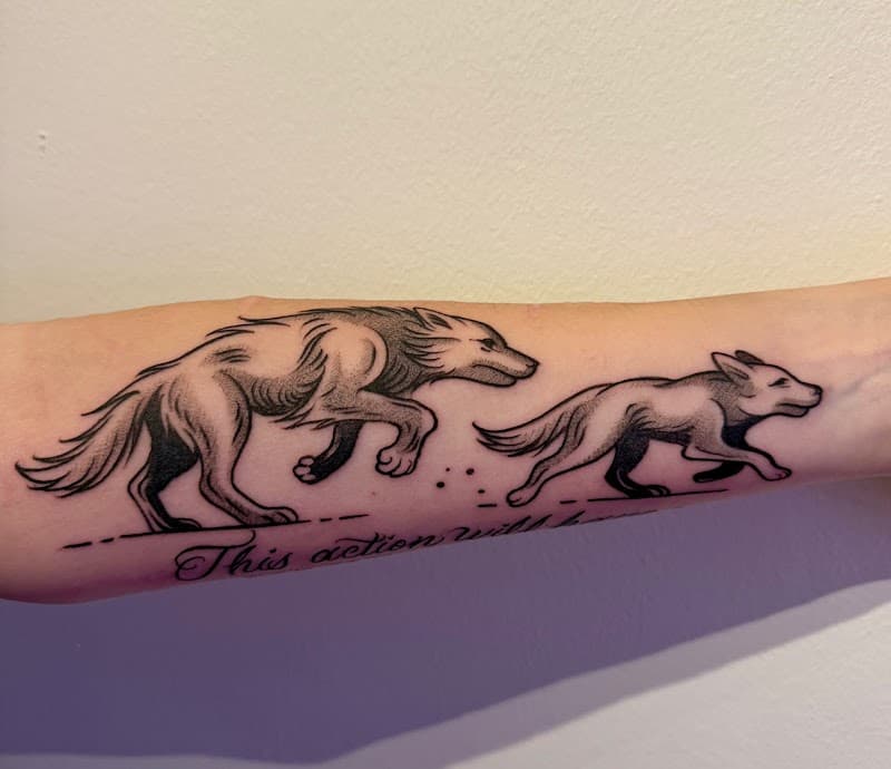 Illustratieve tattoo van twee rennende wolven met tekst op onderarm.
