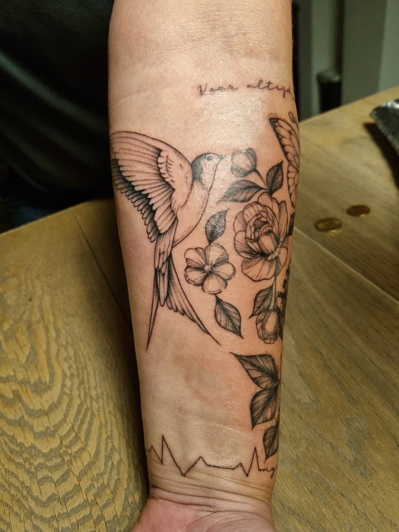 Fineline tattoo van een zwaluw, bloemen, tekst en hartslag op de onderarm.