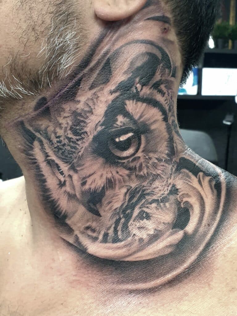 Realistische uil tattoo op de nek, gedetailleerd oog en veren.