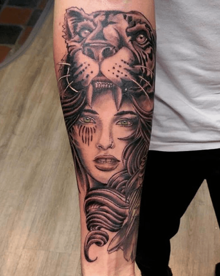 Realistische tattoo van een vrouw met een tijgerhoofdtooi op de onderarm.