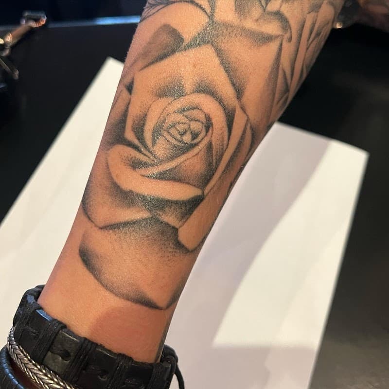 Zwart-grijze roos tattoo op de onderarm.