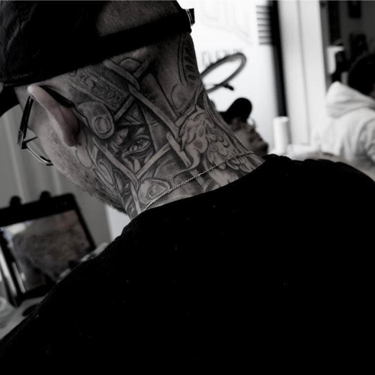 Grote zwart-wit nek tattoo met gedetailleerde architectuur en een oog.