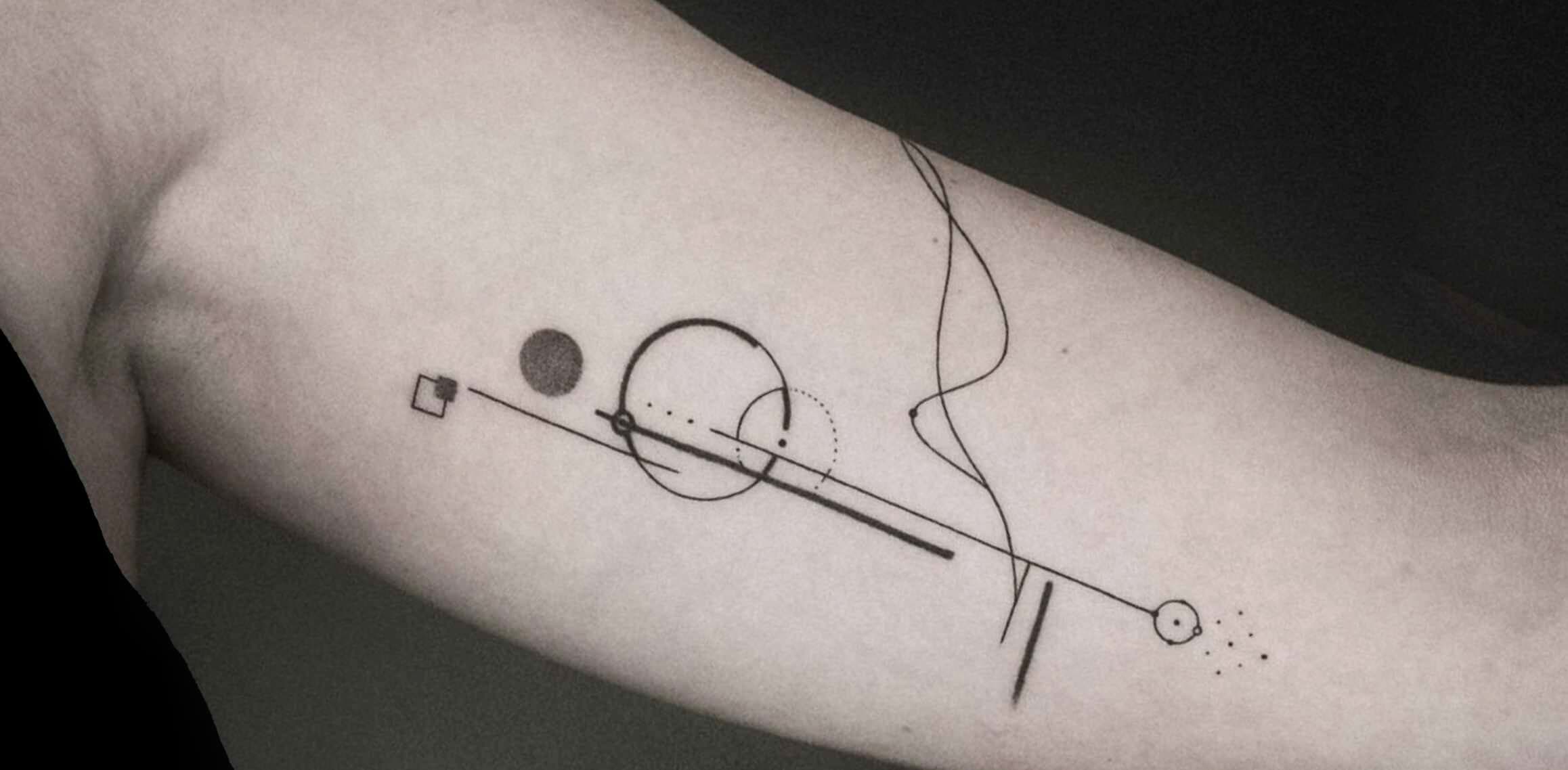 Minimalistische geometrische tattoo met lijnen en cirkels op de bovenarm.