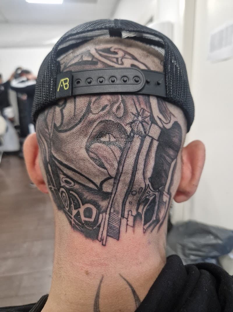 Grote zwart-wit tattoo op achterhoofd met een pistool en een gezicht.