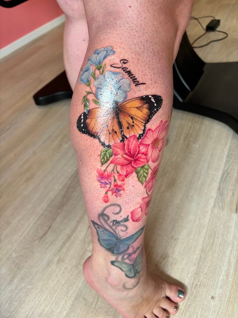 Kleurrijke monarchvlinder met bloemen en de naam 'Samuel' op het onderbeen.
