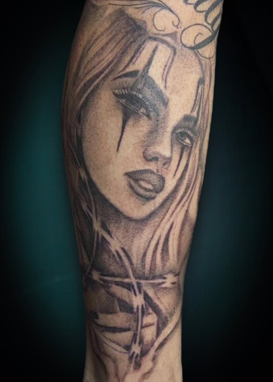 Zwart-wit portret van een vrouw met clownsmake-up en prikkeldraad.