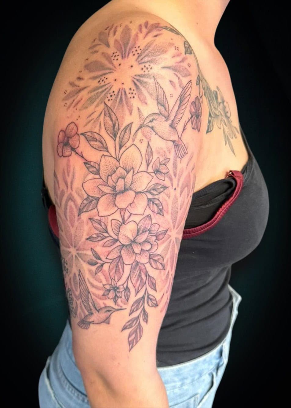 Fineline bloemen en kolibries met geometrische achtergrond op bovenarm.