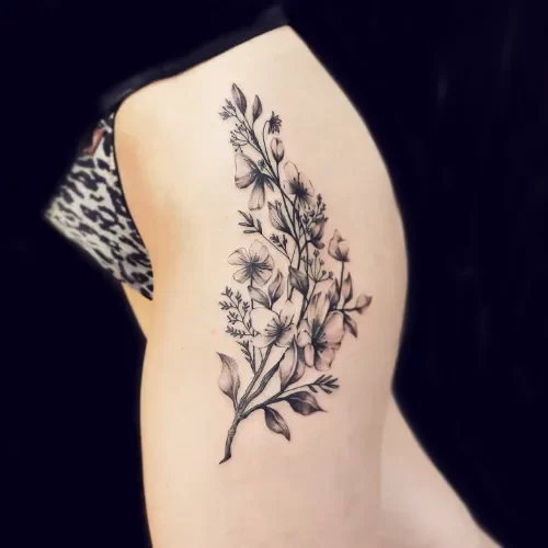 Zwart-wit bloemenboeket tattoo op de heup/bovenbeen.