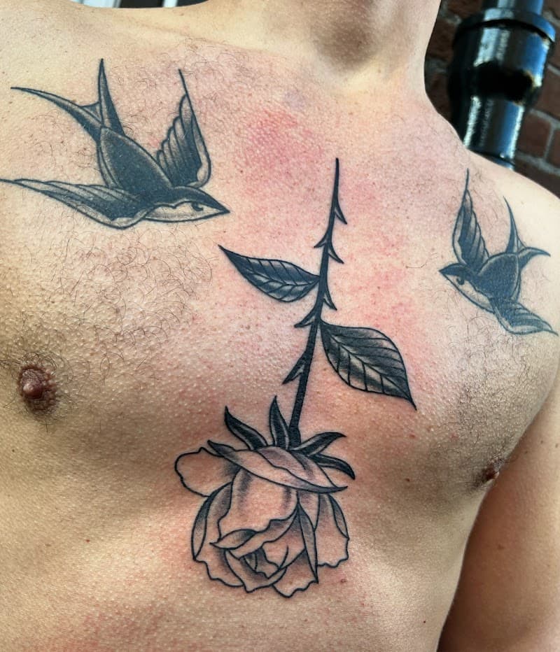 Zwart-wit traditionele roos en twee zwaluwen op borst.