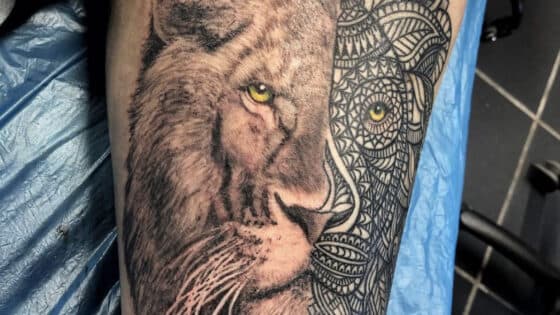 Half realistische, half geometrische leeuwenkop tattoo met gele ogen.