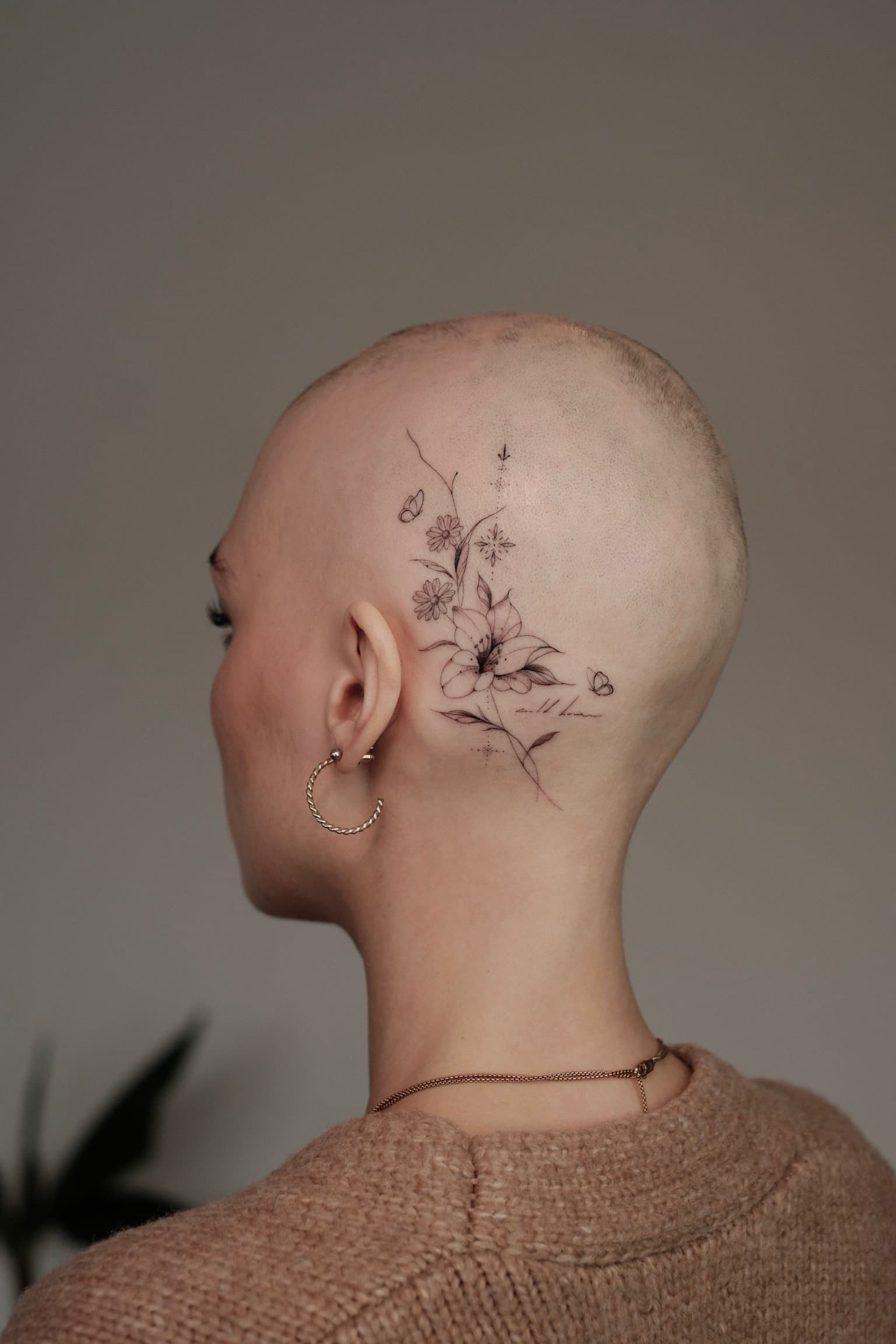 Fineline bloemen en vlinders tattoo achter het oor en op het hoofd.