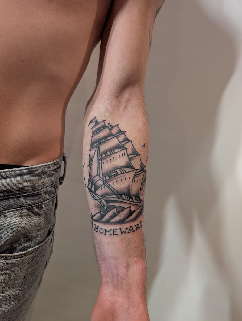 Traditionele zeilschip tattoo met 'HOMEWARD' tekst op onderarm.