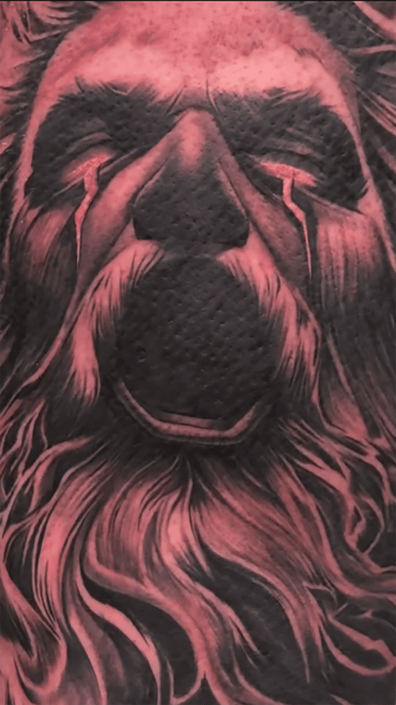 Duistere Zeus tattoo met rode gloeiende ogen en baard.