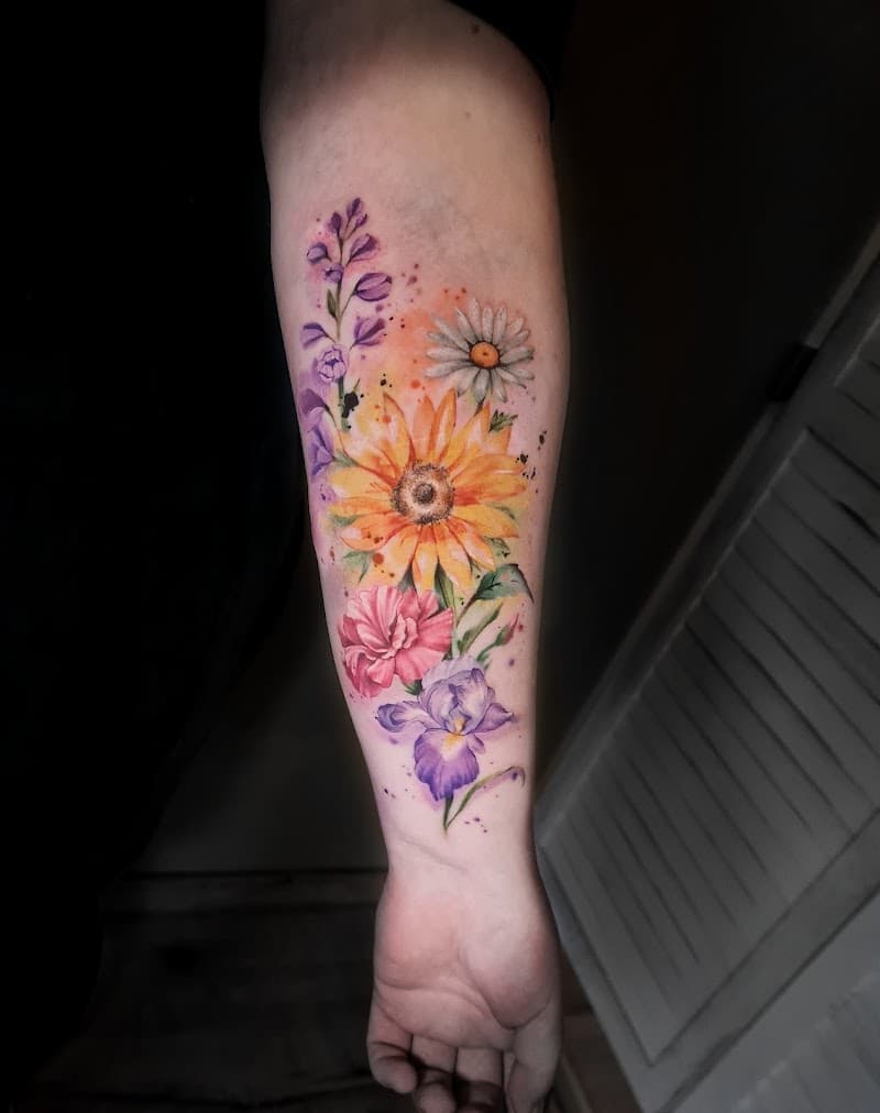 Kleurrijke aquarel bloemen tattoo op onderarm.