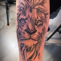 Sketch-style leeuwenkop tattoo op de onderarm.