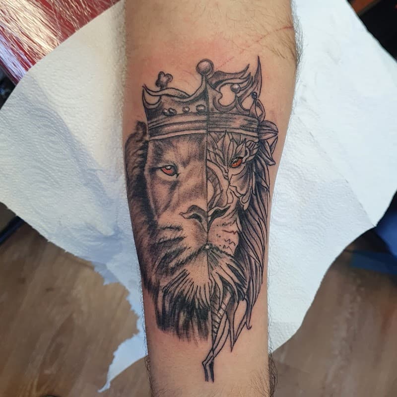 Halve leeuw, halve draak met kroon en rode ogen op onderarm.