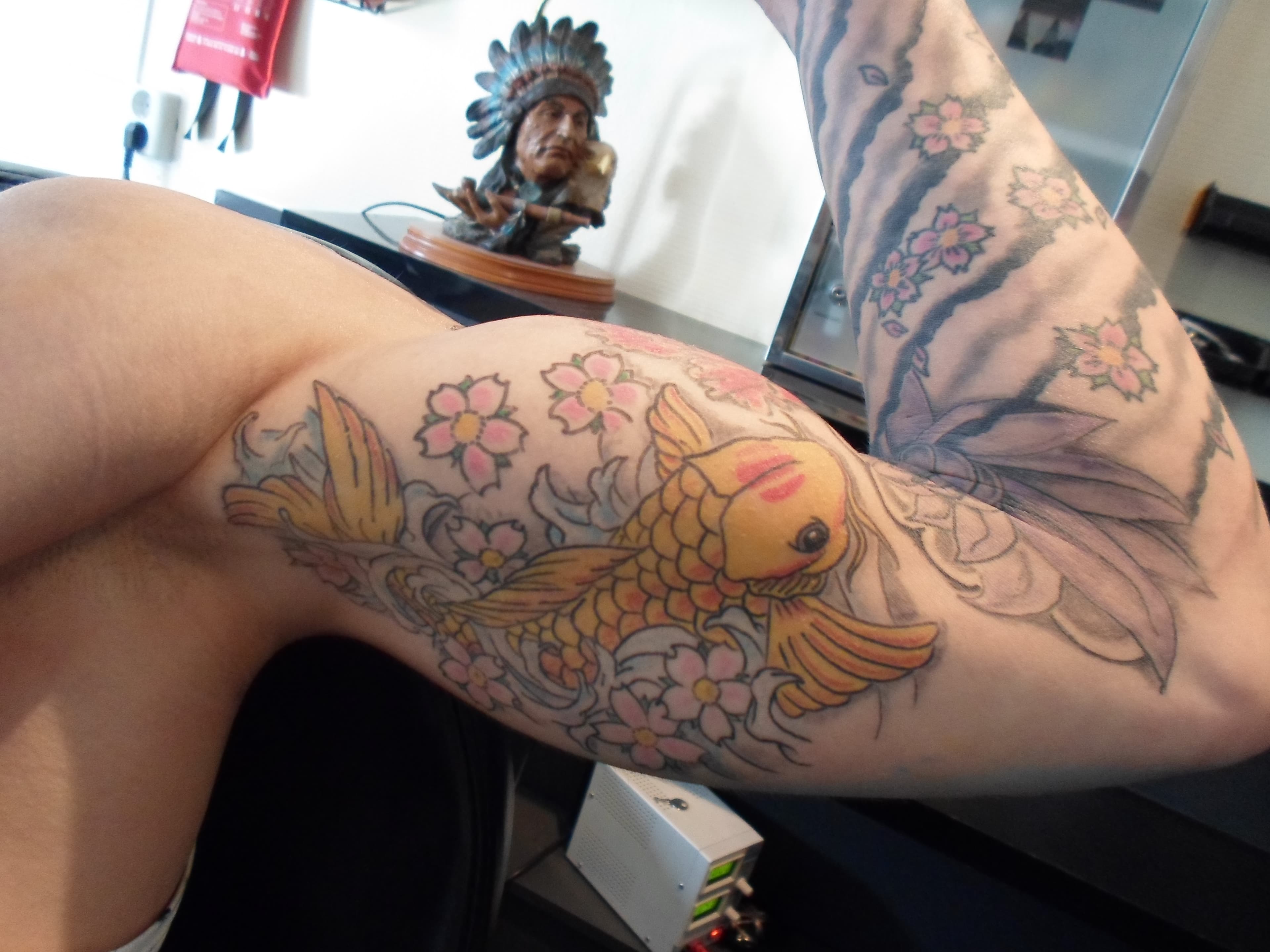 Gele koi karper met roze kersenbloesems op de bovenarm.