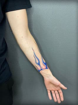 Blauwe vlammen tattoo op de onderarm en pols.